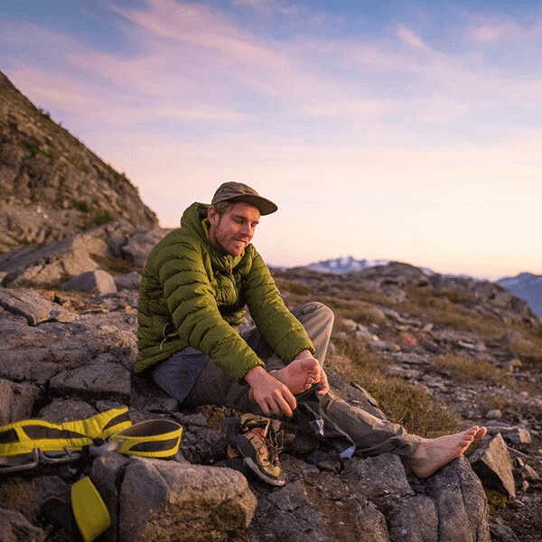 Hiker sitting on stone and holding his foot